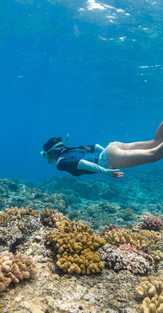 Jeune femme faisant du snorkelling au-dessus d'un récif de corail
