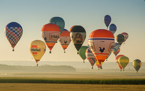 Montgolfières au dessus d'un champ lors du coucher de soleil, durant le championnat d'Europe de montgolfière à Brissac