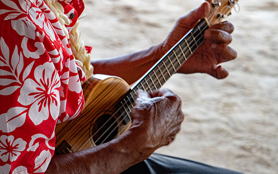 Un homme en chemise fleurie joue du ukulele à Bora Bora