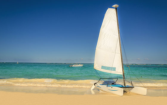 Catamaran blanc sur une plage exotique des Caraïbes sur fond de sable doré, océan bleu azur et ciel bleu