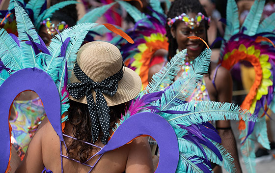 Parade traditionnelle du carnaval de mai, jeune femme de dos déguisée avec des plumes multicolores